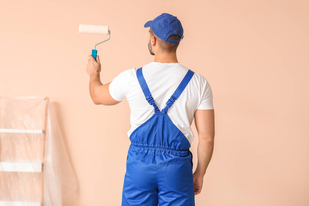 Young painter doing repair in room - Foto, afbeelding