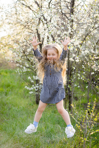 Little blonde girl having fun in the spring park. - Zdjęcie, obraz