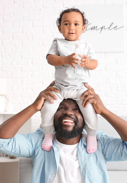 Hombre afroamericano jugando con su lindo bebé en casa
 - Foto, Imagen