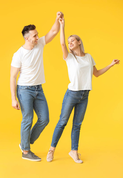 Happy dancing young couple on color background - Foto, afbeelding