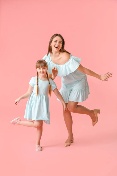 Happy mother and her little daughter dancing against color background - Zdjęcie, obraz