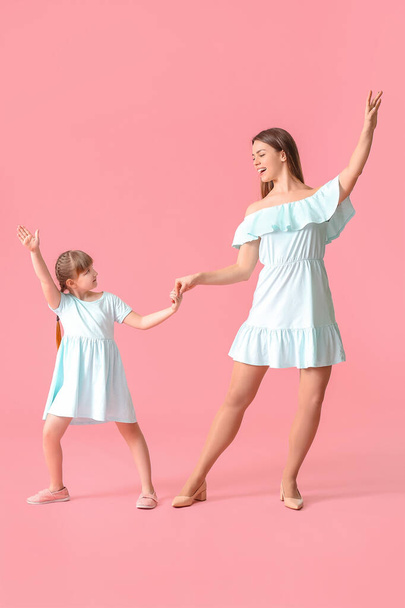Happy mother and her little daughter dancing against color background - Fotoğraf, Görsel