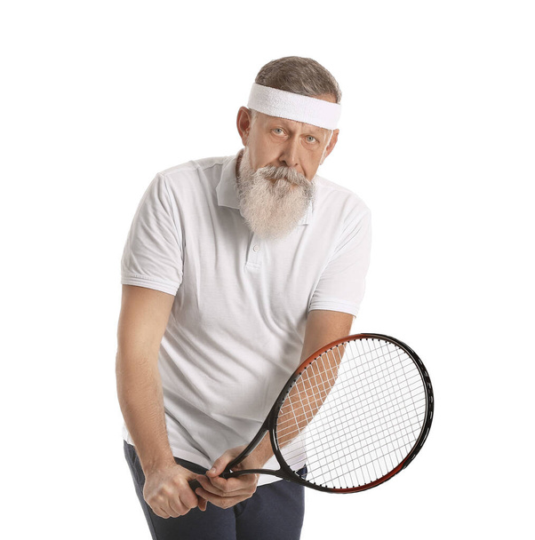 Iäkäs tennispelaaja valkoisella taustalla
 - Valokuva, kuva