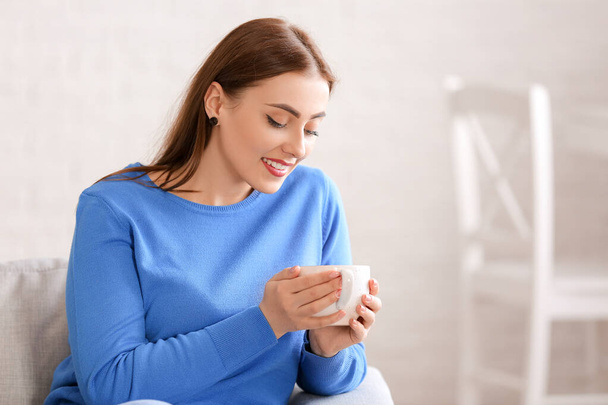 Fiatal nő meleg pulóverben teát iszik otthon - Fotó, kép