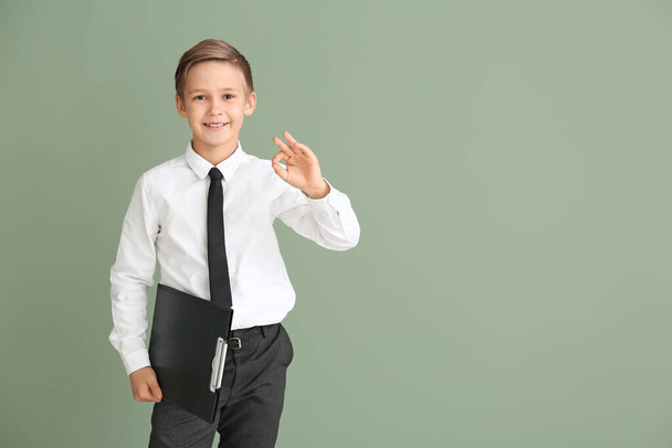 Portrait of little real estate agent showing OK gesture on color background - Фото, изображение