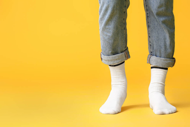 Male legs in socks and jeans on color background - Fotoğraf, Görsel