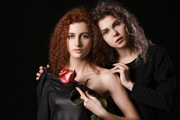 Beautiful young women with flower on dark background - 写真・画像