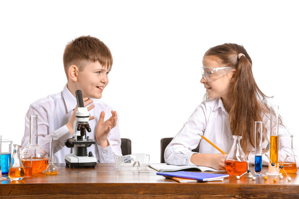 Милые маленькие дети, изучающие химию за столом на белом фоне
 - Фото, изображение