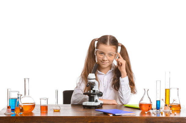 Nettes kleines Mädchen studiert Chemie am Tisch vor weißem Hintergrund - Foto, Bild