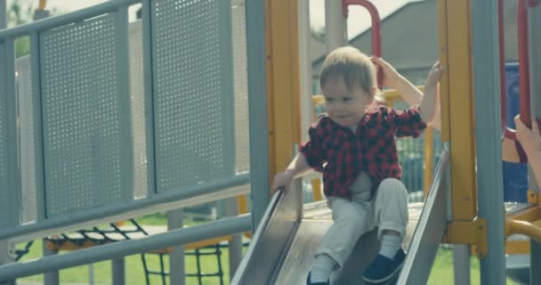 Маленький хлопчик спускається по слайду на дитячому майданчику і чудово проводить час
 - Кадри, відео