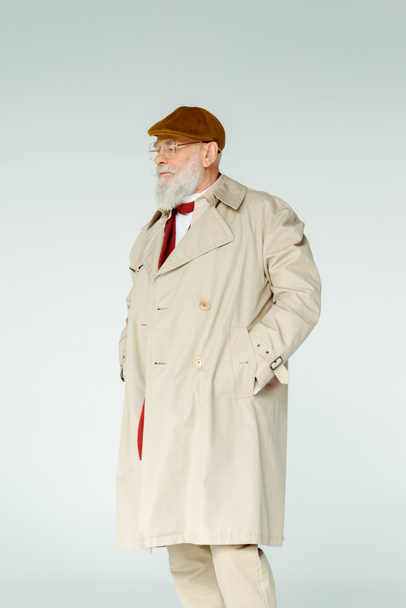 Handsome elderly man in trench coat and eyeglasses looking away isolated on grey - Foto, Bild