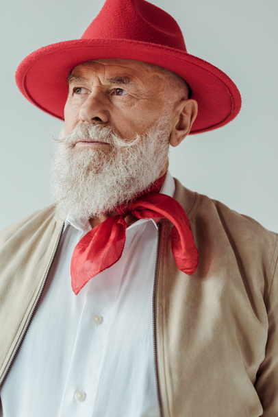 Stylish senior man in red hat looking away isolated on grey - 写真・画像