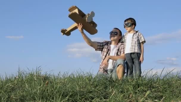 Ojciec i syn bawią się tekturowym samolotem zabawkowym w parku w ciągu dnia. Pojęcie przyjaznej rodziny. Ludzie bawią się na świeżym powietrzu. Obraz wykonany na tle błękitnego nieba. - Materiał filmowy, wideo