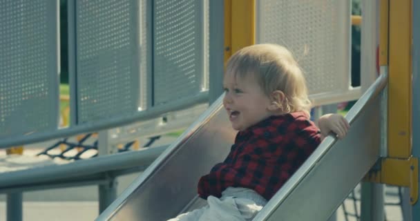 Um menino pequeno está descendo o slide no playground
 - Filmagem, Vídeo