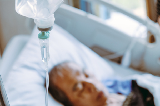 Ältere Patienten im Krankenhausbett Hintergrund, Nahaufnahme von Iv-Kochsalzlösung tropft - Foto, Bild