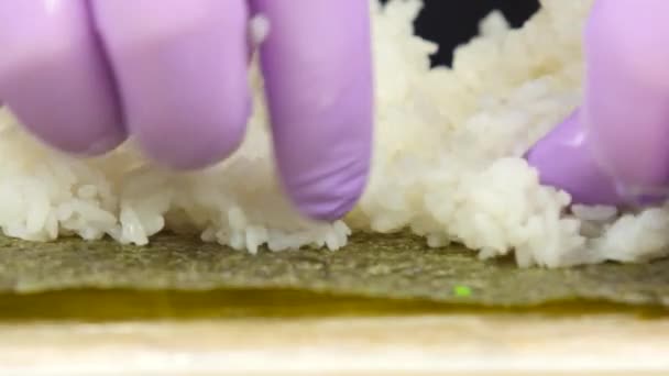 Szef kuchni sushi kładzie biały ryż na prześcieradle nori - Materiał filmowy, wideo