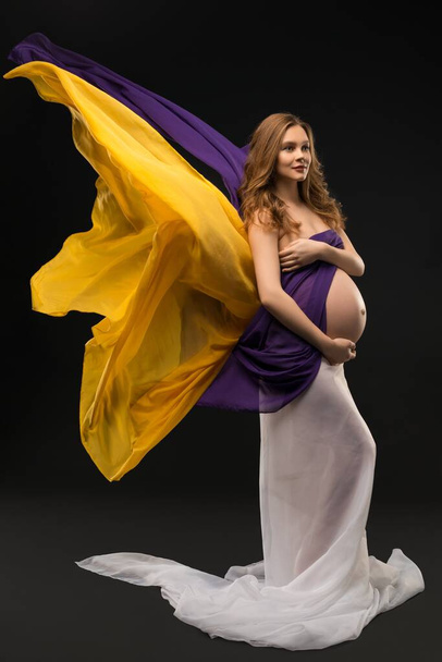 Pregnant woman shot against black background - Fotó, kép