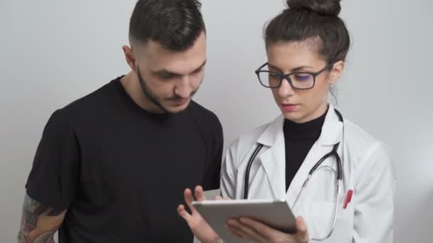  Kobieta Lekarz wyjaśniający wyniki badań medycznych do pacjenta płci męskiej - Materiał filmowy, wideo