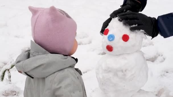 Infant kid with snowman on winter street - Footage, Video