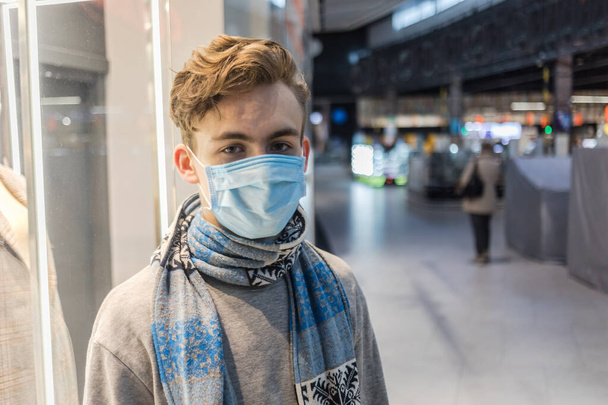 Mladý muž s obličejovou maskou, ochrana proti koronaviru. Covid-19 osoba. Procházky ve velkém nákupním centru, svět uprostřed korony virus situace - Fotografie, Obrázek