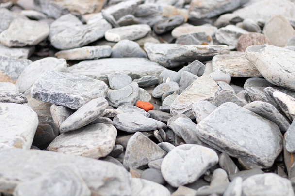 oranžový kámen obklopený spoustou kamenů a šedých skal - Fotografie, Obrázek