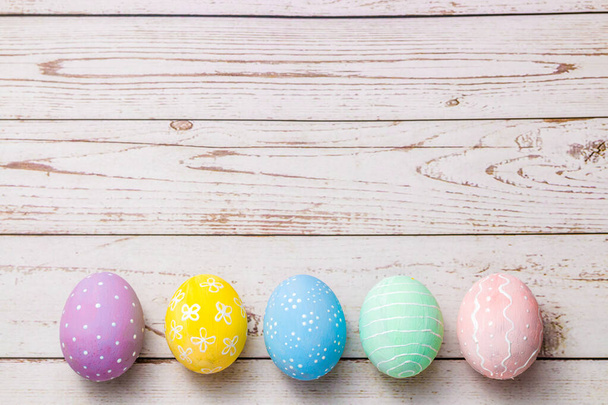 easter background with hand painted pastel colors eggs on light colored wooden table. - Foto, afbeelding