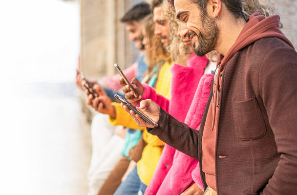 Group of multiracial people standing watching  with their cell phones. Young people always connected to the internet and social network concept. Image fades to pure white to leave room for text. - Photo, Image