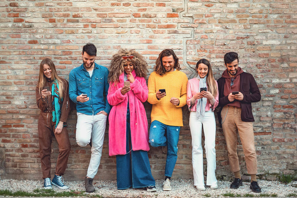 Amigos multirraciais usando smartphone contra uma parede antiga - Jovens viciados por telefone inteligente móvel - Conceito de tecnologia com sempre conectado. usando as mídias sociais. Imagem filtrada
 - Foto, Imagem