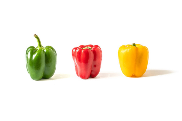 Vihreä, punainen ja keltainen pepperoni eristetty valkoisella pohjalla. Asetelma varjoissa
 - Valokuva, kuva