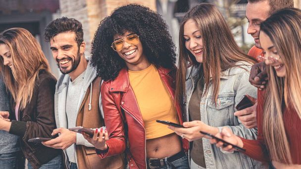 Joyeux groupe d'amis multiraciaux utilisant le smartphone dans le centre ville. Mixed race millennials people lifestyle concept. Amis partageant un voyage en réseau social.  - Photo, image
