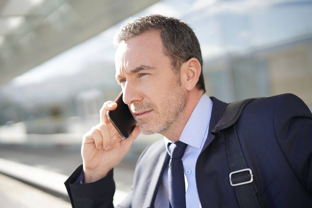 Executive man talking on phone outside exhibition center - Фото, зображення