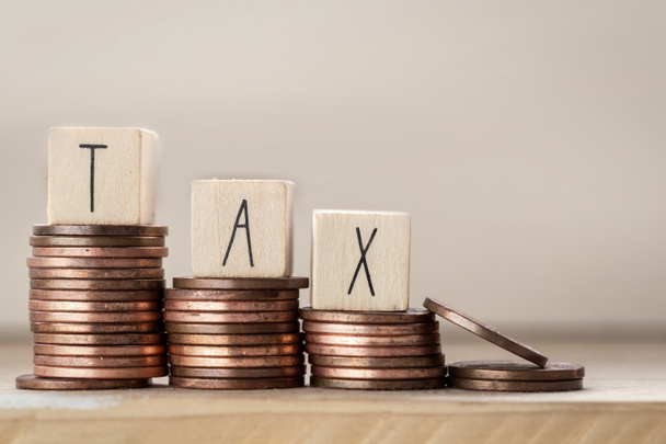 Holzwürfel mit dem Wort Tax on money, Stapel von Münzen, Steuerkonzept Hintergrund - Foto, Bild