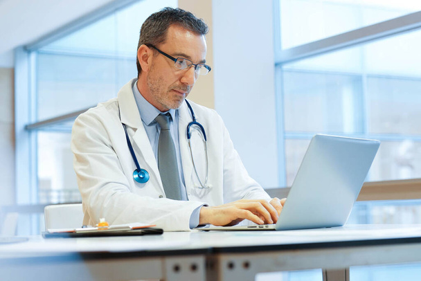 Doctor in hospital office working on laptop - Фото, зображення
