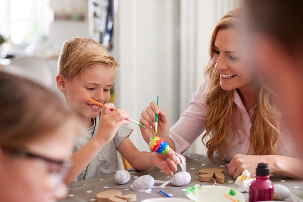 Parents With Children Sitting At Table Decorating Eggs For Easter At Home - Foto, Bild