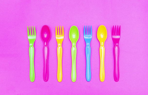 Bovenaanzicht van kleurrijke lepel en vork element op rode kleur tafel.flat lay ontwerp - Foto, afbeelding