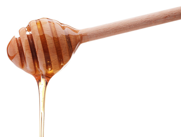 Honey dripping from a wooden honey dipper - Fotoğraf, Görsel