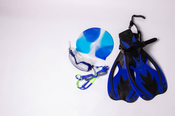 Yüzme şapkalı ve gözlüklü bir çift mavi palet beyaz arka planda mesaj için yer var. - Fotoğraf, Görsel