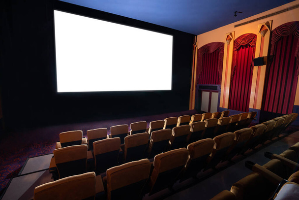 Ekran kina przed rzędami siedzeń w kinie z białym ekranem wyświetlanym z kinematografii. Kino jest urządzone w stylu klasycznym dla luksusowego poczucia oglądania filmów. - Zdjęcie, obraz