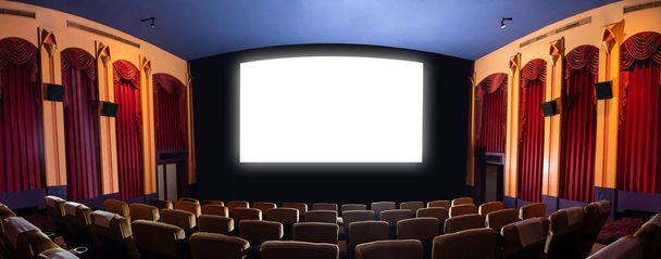 Екран кінотеатру перед рядами сидінь у кінотеатрі, що показує білий екран, спроектований з кінематографа. Кінотеатр оформлений в класичному стилі для розкішного відчуття кіноперегляду
. - Фото, зображення