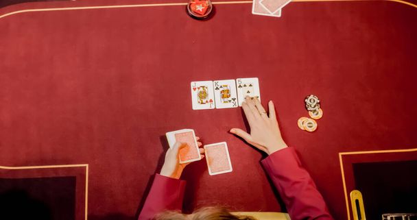 dealer in een casino aan tafel zitten tijdens het bedrijf en verspreiden van kaarten - Foto, afbeelding