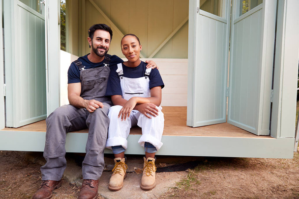 Portrait Of Couple Taking A Break From Building Outdoor Summerhouse In Garden - Фото, изображение