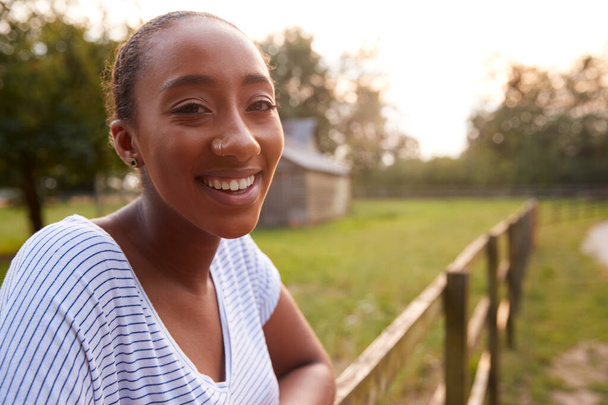 Portrait Of Smiling Young Woman Taking A Break And Resting On Fence During Walk In Countryside - Fotó, kép