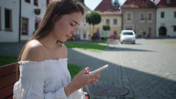 woman is browsing internet by smartphone in square - Záběry, video