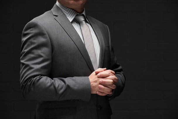 obchodník portrét oblečený v šedém obleku, tmavé stěny pozadí - Fotografie, Obrázek