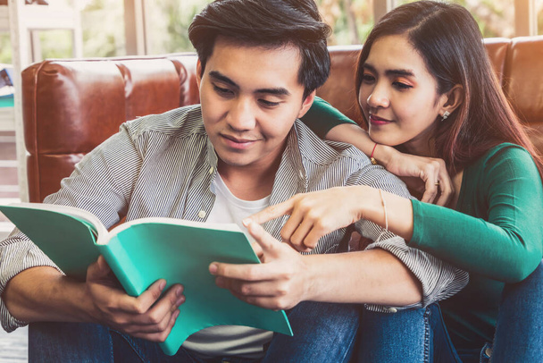 Fiatal ázsiai pár könyvet olvas a nappaliban. Szerelmi kapcsolat és életmód koncepció. - Fotó, kép