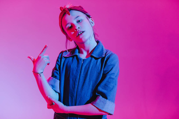 Jong stijlvol meisje in de Studio op een gekleurde neon achtergrond. Muziek dj poster ontwerp. Portret van een jonge danseres. - Foto, afbeelding