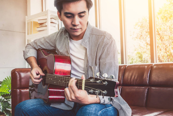 Young guitar player holding his guitar at home. Music and song concept. - Fotoğraf, Görsel