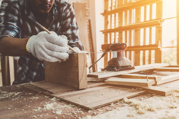 Carpintero trabajando en artesanía de madera en el taller para producir material de construcción o muebles de madera. El joven carpintero asiático utiliza herramientas profesionales para la elaboración. Fabricante de bricolaje y carpintería concepto de trabajo. - Foto, Imagen