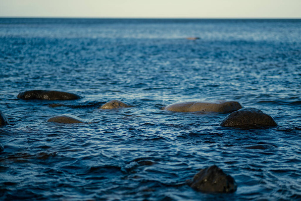 Kumsalda mavi su ve kumda büyük kayalar olan güneşli bir sahil. Letonya açık gökyüzü altında - Fotoğraf, Görsel