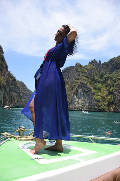 Phi Phi adasının yeşil kayalarının etrafındaki bir teknenin pruvasında güzel bir kız. - Fotoğraf, Görsel